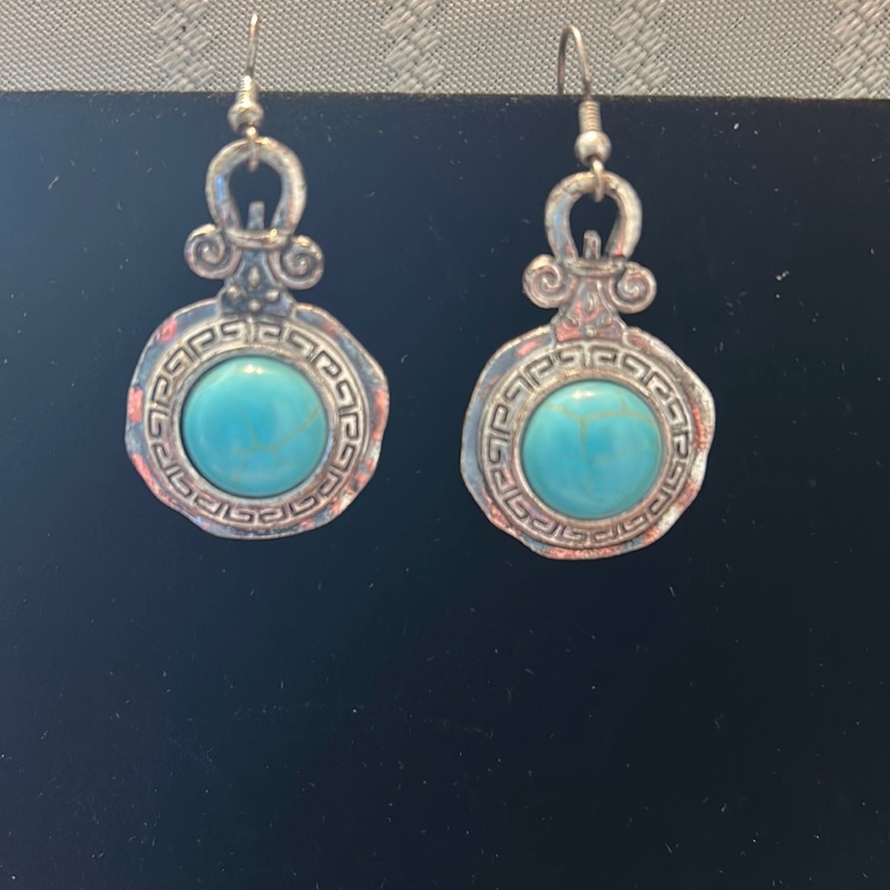 Silver medallion design earrings with turquoise colored stones in the center.